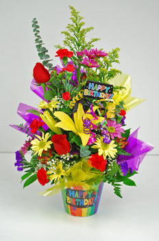 It’s their birthday. Why not make it special. Our “Birthday Fireworks” will turn any birthday into a party. This Happy Birthday container is filled with colorful yellow Asiatic lilies, red roses, yellow and purple daisies, red mini carnations with yellow 