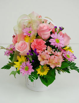 This charming white basket is filled with pink roses, pink carnations, yellow and lavender daisies, pink wax flower, purple statice, mixed greenery, and tied with a matching ribbon. No matter what the occasion, our "Blossom Buddies" will make it extra spe