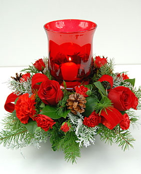 Our “Home Spun Holiday” arrangement starts with a large red glass globe candle holder surrounded with holiday evergreens, red carnations, pine cone, holly and flocked evergreens. The glow of the candle reminds us of the times we’ve spent with family and f