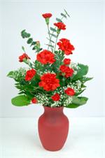 Ruby red glass garden vase over flowing with rich red carnations and mixed greenery. No matter what the occasion flowers just make it extra special