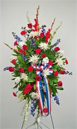 Standing red roses with white spiders mums, red carnations, white stock, red glads, blue delphiniums, and mixed greens. Standing on a 54” easle with red white and blue ribbons, our “color guard” arrangement is a fitting tribute to honor for a military ser