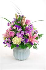 Overflowing with flowers and colors is our  Florabundance. Designed in a white glass vase are green hydrangeas, pink stargazers, purple stock, pink roses, purple statice, mixed greens and lilly grass. For that special occassion, or for that special person