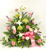 A beautiful sympathy arrangement featuring white Asiatic lily, green spider chrysanthemums, purple liatris, with white roses, pink carnations, baby eucalyptus and mixed greens. Also added to the arrangement is purple statice tissue and pink ribbons. Appro