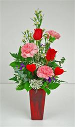 “Kiss Me Quick” has everything that say, “Happy Valentine Day”. Designed in a valentine day red glass vase, are two valentine red roses, with three cotton candy pink carnations, white monti casino, million star gyp with purple statice, mixed greens and ba