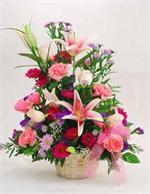 White wicker basket filled pink stargazers lilies, pink carnations,lavender daisies,filler and mixed greenery.