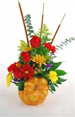 A harvest of flowers in the warm colors of fall, the perfect accompaniment for your autumn festivities. This ceramic pumpkin has a “stem” as its lid, and holds a stunning bouquet of orange lilies with orange roses, red carnations and yellow button pomps,w