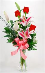 Three Stargazers Lilies with three roses and mixed greens, Million Star Gyp all arranged in a glass garden vase.