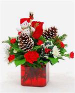 Red glass cube filled with holiday evergreens, pine cones holly, red glass ornaments, baby breath, red mini carnations, and to make it extra special, we added red roses.